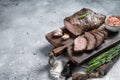 Roast and sliced tri tip beef steak on a wooden board with herbs. Gray background. Top view. Copy space Royalty Free Stock Photo