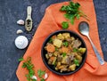 Roast, stewed beef with potatoes and carrots in a brown clay bowl on a dark concrete background