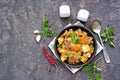 Roast, stewed beef with potatoes and carrots in a brown clay bowl on a dark concrete background