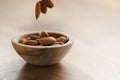 Roasted almonds falling in wood bowl on wooden table Royalty Free Stock Photo