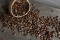 Roasted arabica coffee beans scattered on a wooden table from a coconut. Fresh coffee beans.