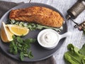 Roasted baked salmon fillet with lemon, white sauce and spinach close up