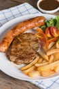 Roasted beef meat steak and sausage with french fries. Royalty Free Stock Photo