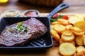 Roasted beef steak with potato wedges on a cast iron skillet. Royalty Free Stock Photo