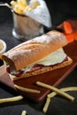 Roasted Beef Sub Sandwich with french fries bucket served on wooden board isolated on dark background side view of breakfast food Royalty Free Stock Photo