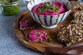Roasted beet hummus in ceramic bowl, flax seed crackers on wooden cutting board, pesto sauce jar - vegetarian, vegan food concept