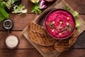 Roasted Beet Hummus with toast in a ceramic bowl on a dark background.