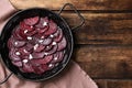 Roasted beetroot slices with feta cheese in wok pan on wooden table, flat lay. Space for text