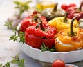 Roasted bell pepper with mushroom, rice, cheese and herbs filling in a baking dish on a white wooden table, close-up.