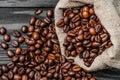Roasted brown coffee beans falling out from the burlap bag on the table Royalty Free Stock Photo