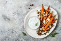 Roasted carrots lentil salad with feta, herb yogurt and dukkah on a light concrete background. Vegetarian food.