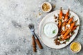Roasted carrots lentil salad with feta, herb yogurt and dukkah on a light concrete background. Vegetarian food.
