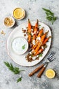 Roasted carrots lentil salad with feta, herb yogurt and dukkah on a light concrete background. Vegetarian food.