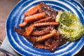 Roasted carrots and mashed avocado on a ceramic plate side view