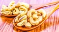 Roasted cashew nuts on a wooden spoon.Roasted salted cashew nuts on white background