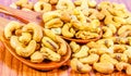 Roasted cashew nuts on a wooden spoon.Roasted salted cashew nuts on white background. Healthy food, cashews rich in heart friendly