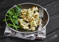 Roasted cauliflower and fresh arugula on a brown plate Royalty Free Stock Photo