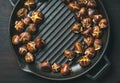 Roasted chestnuts in grilling pan over dark scorched wooden background