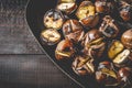 Roasted chestnuts in cast iron grilling pan over rustic wooden board Royalty Free Stock Photo