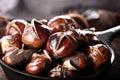 Roasted chestnuts served in a special perforated chestnut pan on an old wooden table. Royalty Free Stock Photo