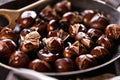 Roasted chestnuts served in a special perforated chestnut pan on an old wooden table. Royalty Free Stock Photo