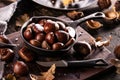 Roasted chestnuts served in a special perforated chestnut pan on an old wooden table. Royalty Free Stock Photo