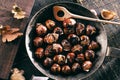 Roasted chestnuts served in a special perforated chestnut pan on an old wooden table. Royalty Free Stock Photo