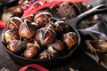 Roasted chestnuts served in a special perforated chestnut pan on an old wooden table. Royalty Free Stock Photo