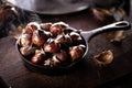 Roasted chestnuts served in a special perforated chestnut pan on an old wooden table. Royalty Free Stock Photo