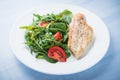 Roasted chicken breast and fresh salad with tomato and greens (spinach, arugula) close up on blue wooden background Royalty Free Stock Photo