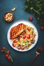 Roasted chicken breast with tabbouleh salad with bulgur, tomatoes and parsley with oil lemon dressing, green table background, top