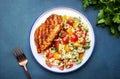 Roasted chicken breast with tabbouleh salad with bulgur, tomatoes and parsley with oil lemon dressing, green table background, top