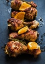 Roasted chicken legs, oranges and rosemary on the black background