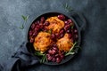 Roasted chicken legs with red grapes on pan over black slate stone background. Royalty Free Stock Photo