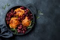 Roasted chicken legs with red grapes on pan over black slate stone background. Royalty Free Stock Photo