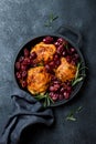 Roasted chicken legs with red grapes on pan over black slate stone background. Royalty Free Stock Photo