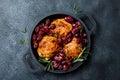 Roasted chicken legs with red grapes on pan over black slate stone background. Royalty Free Stock Photo