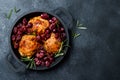 Roasted chicken legs with red grapes on pan over black slate stone background. Royalty Free Stock Photo