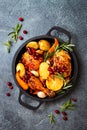 Roasted chicken legs with root vegetables, lemon, garlic, cranberry and rosemary on pan