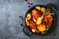 Roasted chicken legs with root vegetables, lemon, garlic, cranberry and rosemary on pan