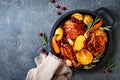Roasted chicken legs with root vegetables, lemon, garlic, cranberry and rosemary on pan