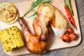 Roasted chicken legs on wooden cutting board with corn lemon chilli spicy herbs spices Royalty Free Stock Photo