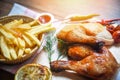 Roasted chicken legs on wooden cutting board and french fries basket with corn lemon chilli spicy herbs spices Royalty Free Stock Photo