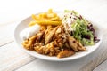 Roasted chicken meat from a doner kebab with french fries, salad and tzatziki dip on a plate and on a wooden table, copy space, Royalty Free Stock Photo