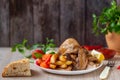 Roasted chicken, potatoes and vegetables in plate on wooden background. Side view