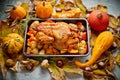 Roasted chicken or turkey garnished with pumpkins, pepper and potatoes. Served on a rustic table