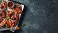 Roasted chicken wings in barbecue sauce with sesame seeds and parsley in a baking tray on a dark table. Top view with copy space. Royalty Free Stock Photo