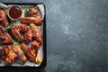 Roasted chicken wings in barbecue sauce with sesame seeds and parsley in a baking tray on a dark table. Top view with copy space. Royalty Free Stock Photo