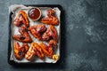 Roasted chicken wings in barbecue sauce with sesame seeds and parsley in a baking tray on a dark table. Top view with copy space. Royalty Free Stock Photo