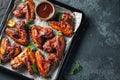 Roasted chicken wings in barbecue sauce with sesame seeds and parsley in a baking tray on a dark table. Top view with copy space. Royalty Free Stock Photo